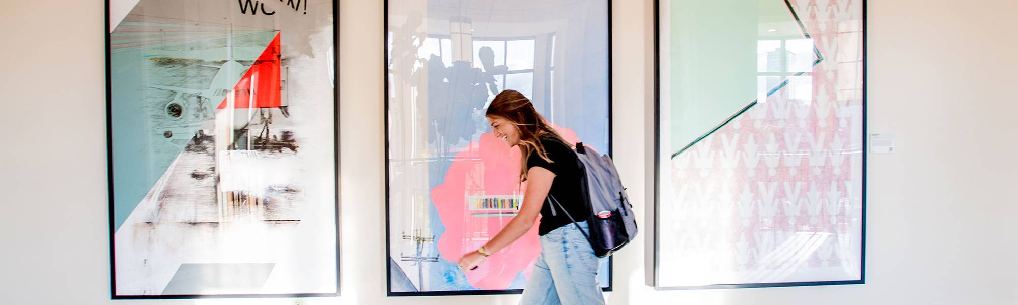student walks in front of art on the city campus
